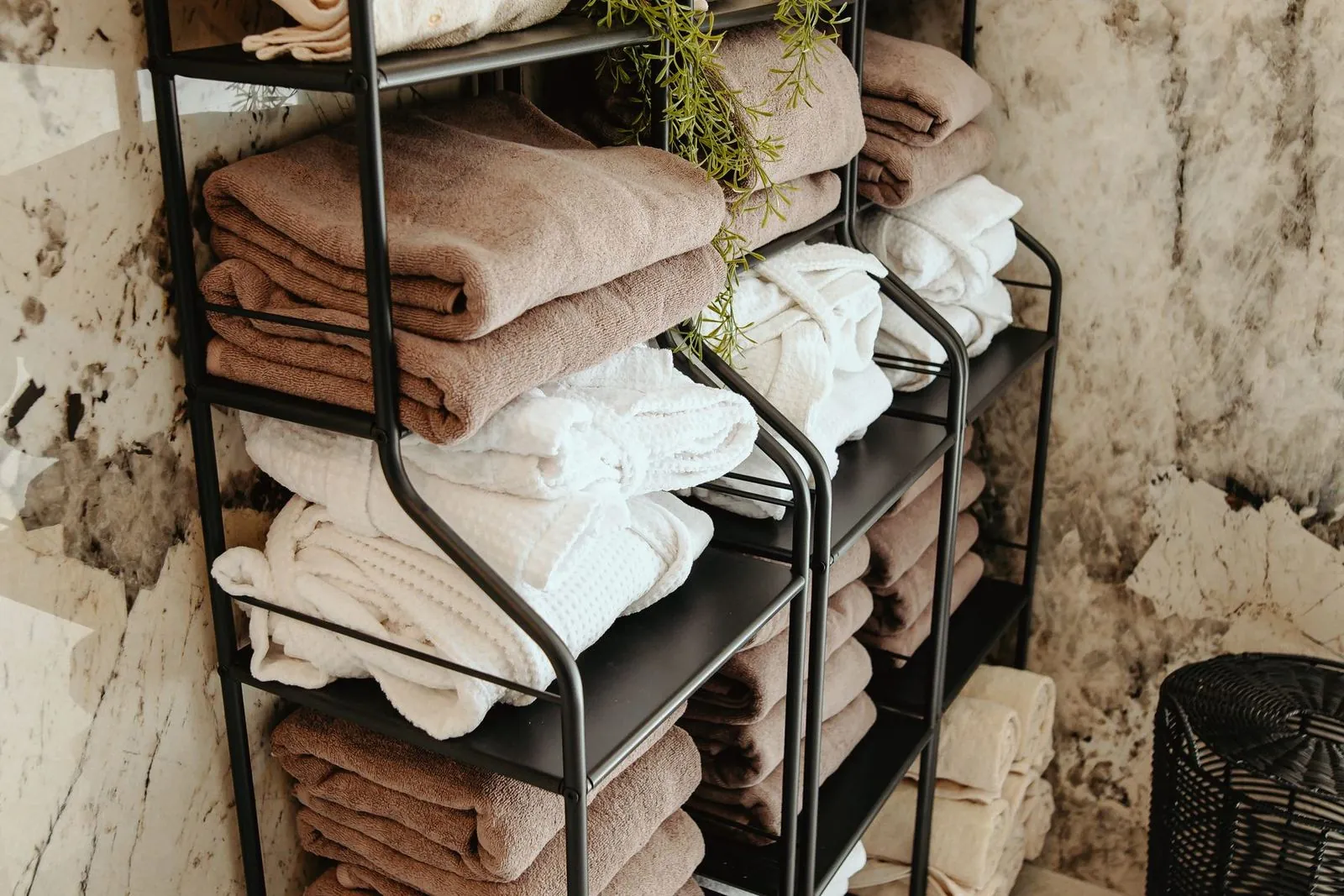 Shelf with folded towels by a marble wall