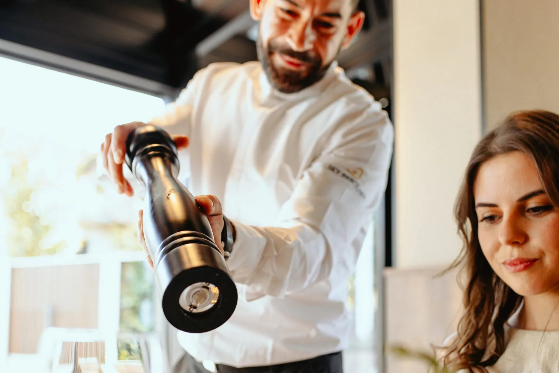 Waiter grinding pepper at a guest's table