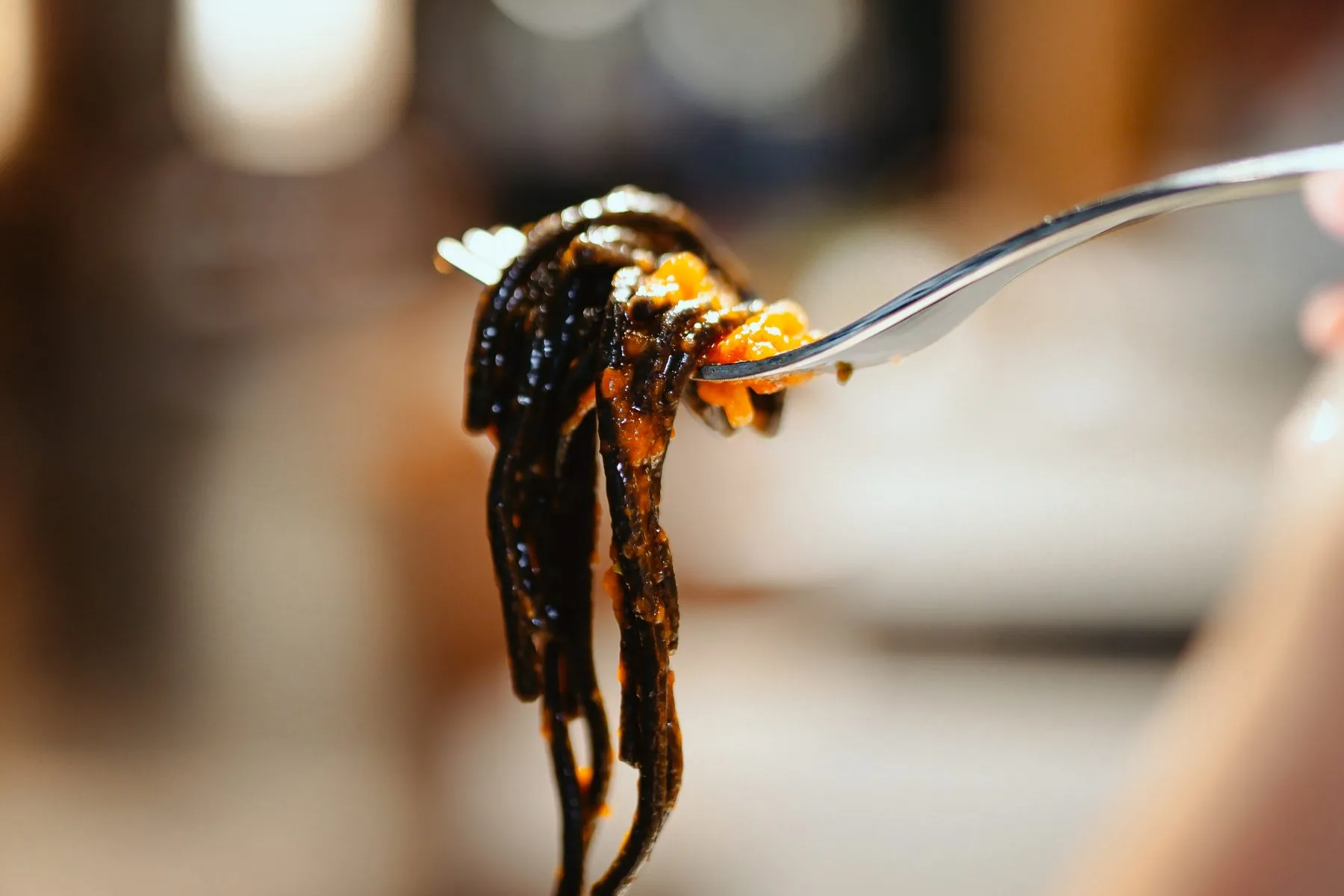 A forkful of black pasta above the table